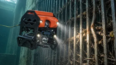 ROV inspecting an underwater trash rack with bent bars and packed debris at a hydropower intake